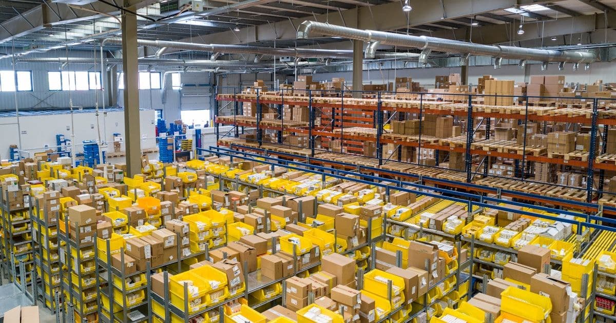 A large warehouse distribution center with rows of shelving and workers managing inventory