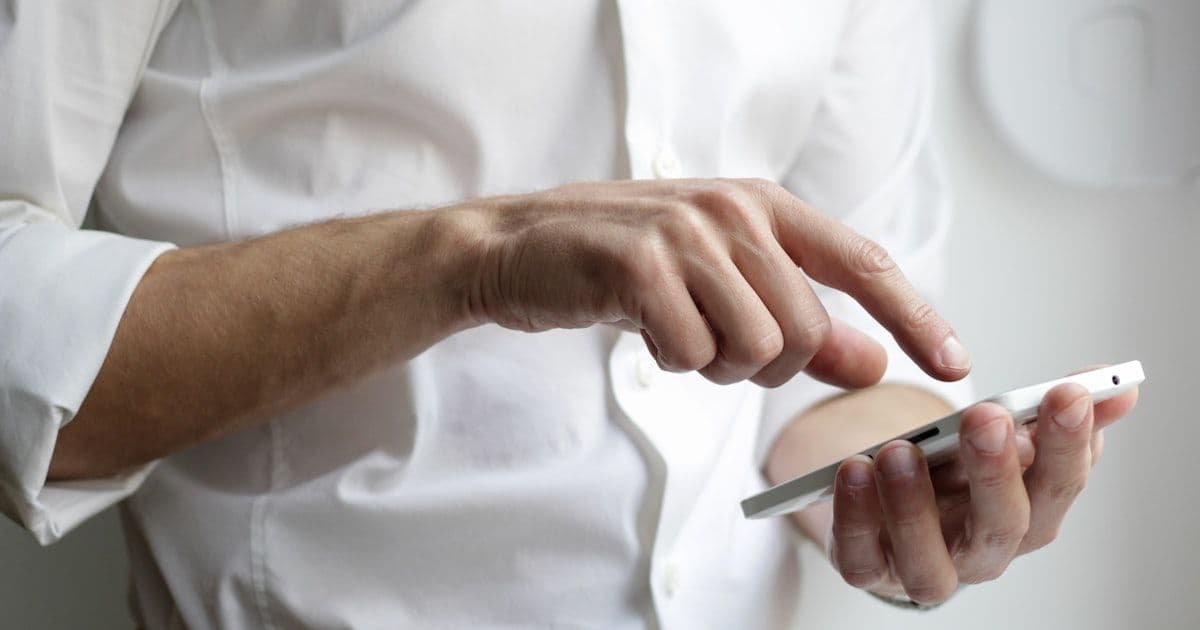 A business professional holding a smartphone, representing the choice between custom mobile app and web app development
