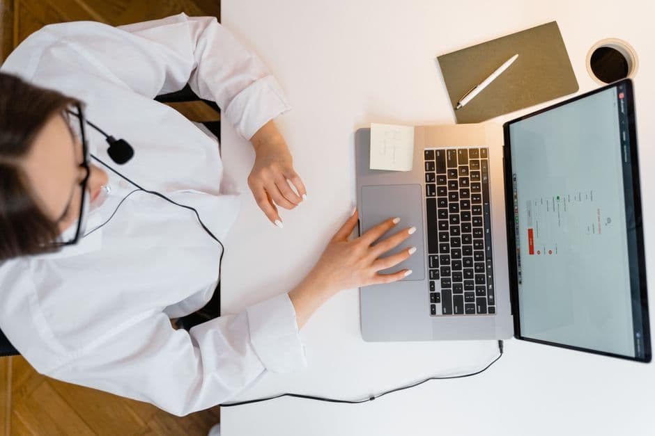 A call center agent wearing a headset works on her laptop in a bright, modern office.